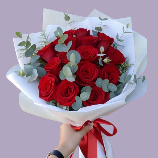 Bouquet of red roses wrapped in white paper with a red ribbon