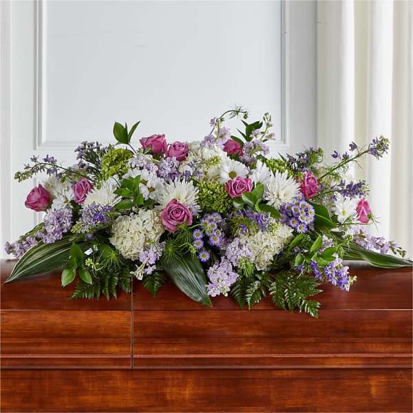 Casket spray with pink roses, white flowers, and purple accents