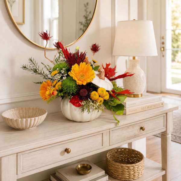 Colorful floral arrangement in a white pumpkin vase on a console table