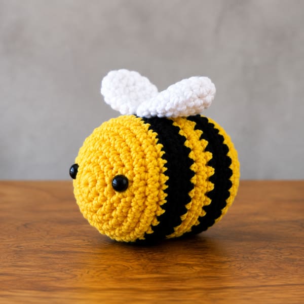 Crocheted bee plush with yellow and black stripes and white wings