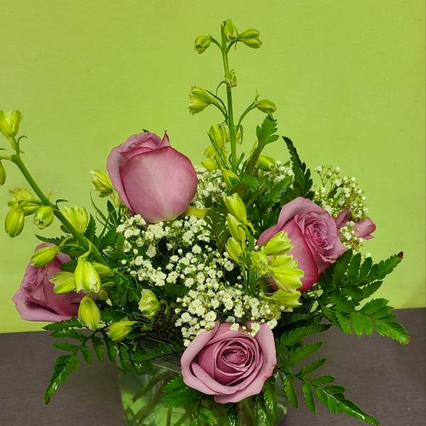 Pink roses and white filler flowers in a green glass vase