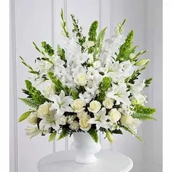 Large white arrangement of lilies and roses in a white pedestal vase