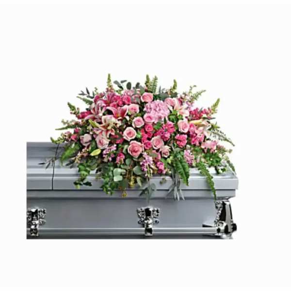 Large pink and white floral casket spray with cascading greenery on a silver casket
