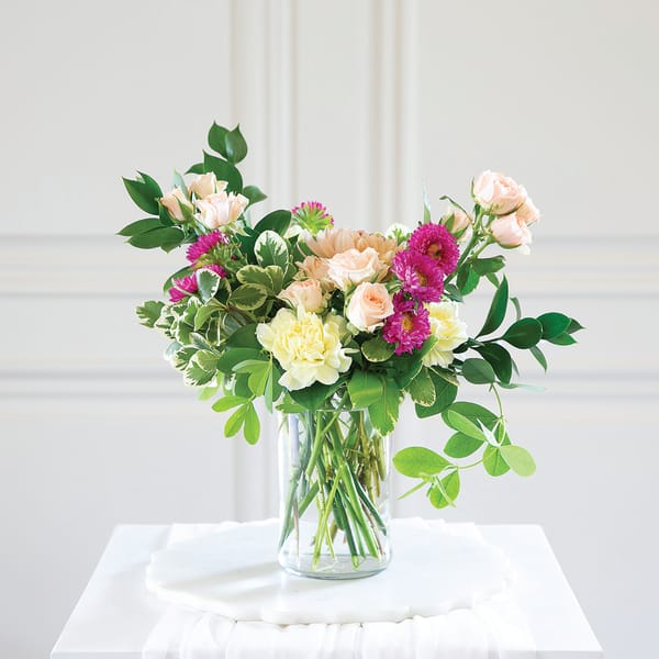 Mixed bouquet of pastel roses and chrysanthemums in a clear glass vase