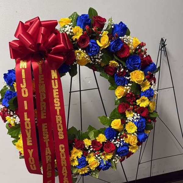 Large floral wreath with red, blue, and yellow flowers and a red ribbon