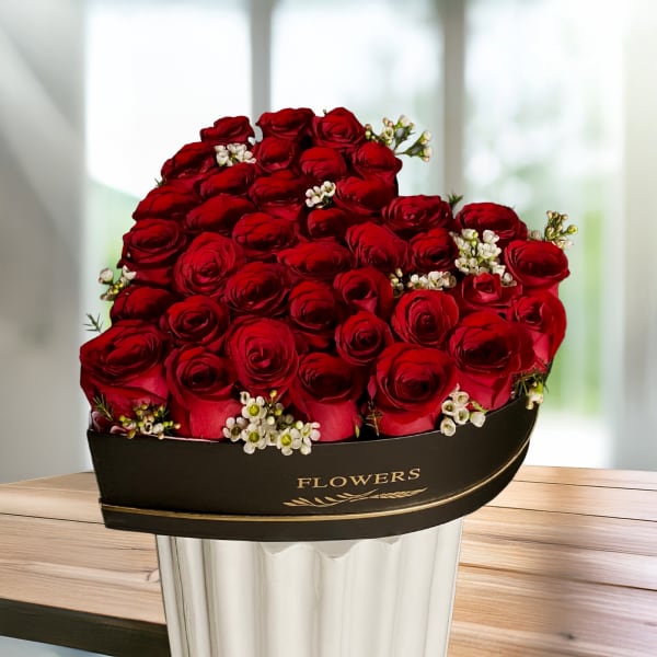 Red rose bouquet in a black hatbox with small white filler flowers
