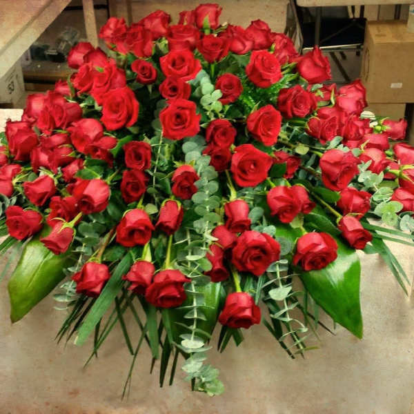 Large bouquet of red roses with greenery on a table