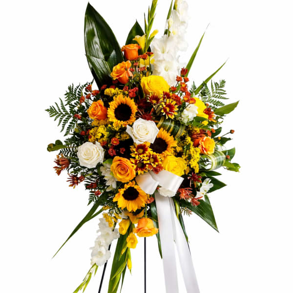 Standing floral spray with yellow, orange, and white blooms on a black easel