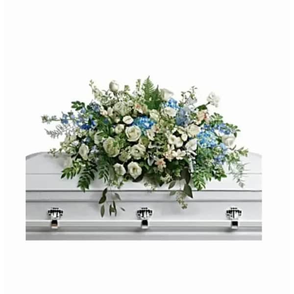 White and blue mixed flower casket spray arranged on top of a white casket