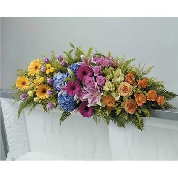 Colorful casket spray with pink lilies, roses, gerbera daisies, hydrangeas, and mixed blooms.