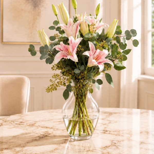 Pink lilies in a clear glass vase with eucalyptus