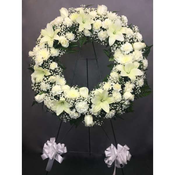 White funeral wreath on a stand with ribbon bows