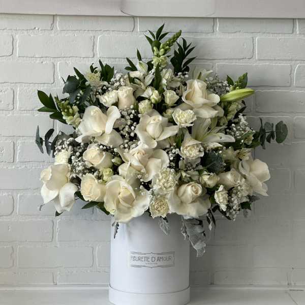 White floral arrangement in a tall white hatbox with roses and lilies