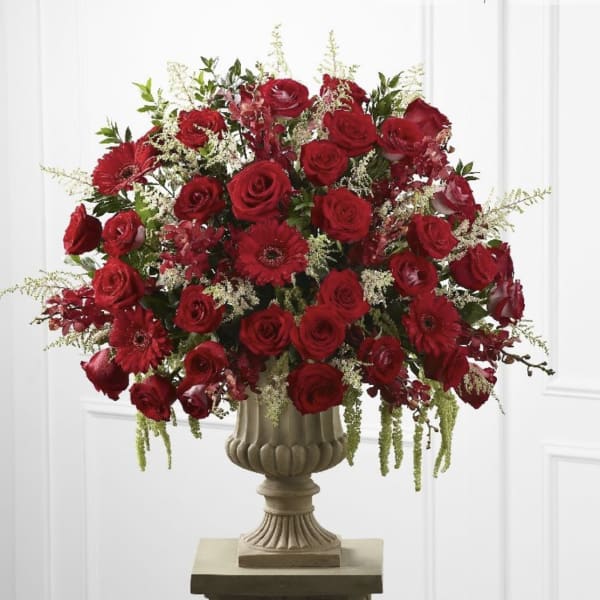 Large red rose arrangement in a decorative pedestal vase