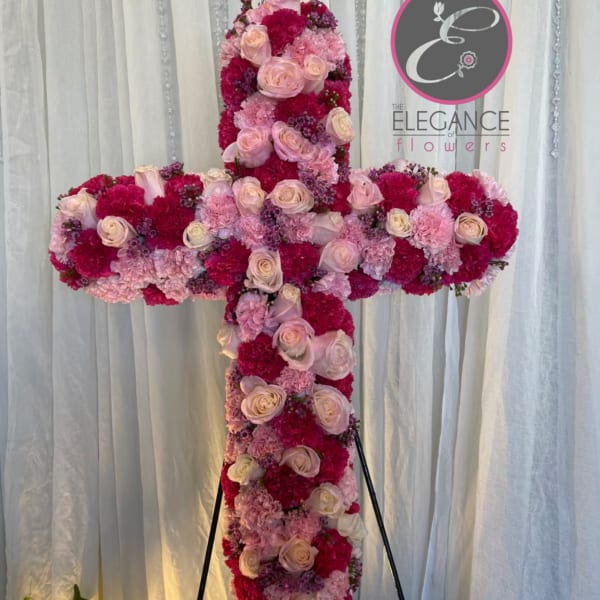 Cross-shaped floral tribute with pink and white roses on an easel