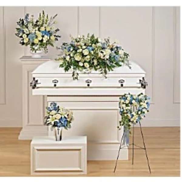 White casket with blue and white floral sprays in a funeral room
