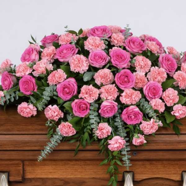 Pink rose and carnation spray on a wooden casket