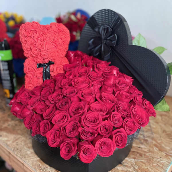 Heart-shaped rose arrangement in a black box with a small rose teddy bear