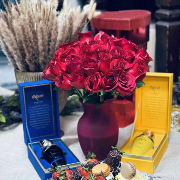 Red rose bouquet in a vase with chocolate-covered strawberries and gift boxes