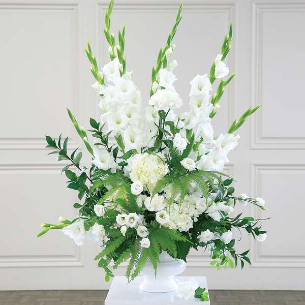 White floral arrangement in a white vase with tall green spikes