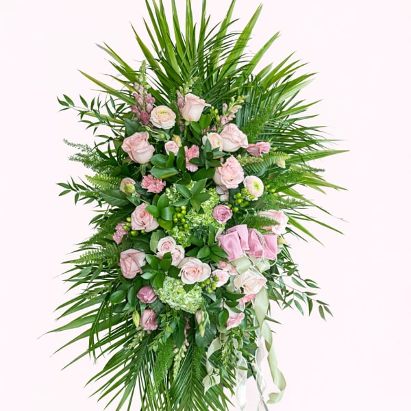 Standing floral spray with pink roses and greenery on a metal easel