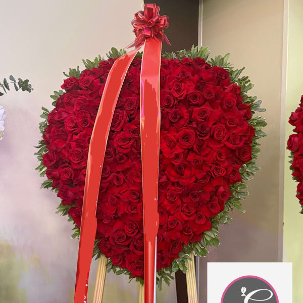 Heart-shaped red rose standing spray with a ribbon on an easel