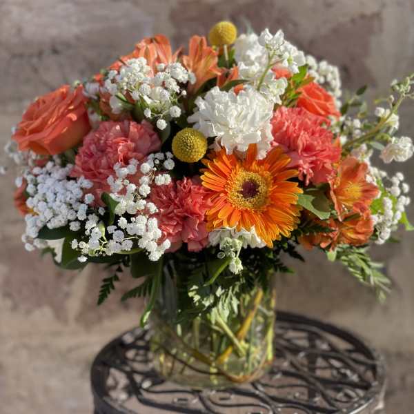 Mixed bouquet of orange, pink, and white flowers in a glass vase