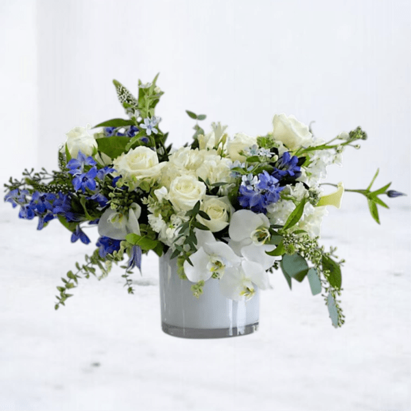 White and blue floral arrangement in a clear glass vase