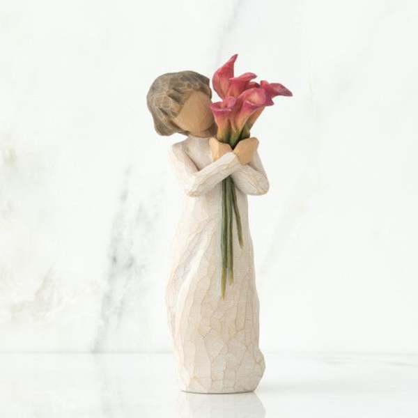 Decorative figurine holding pink calla lilies
