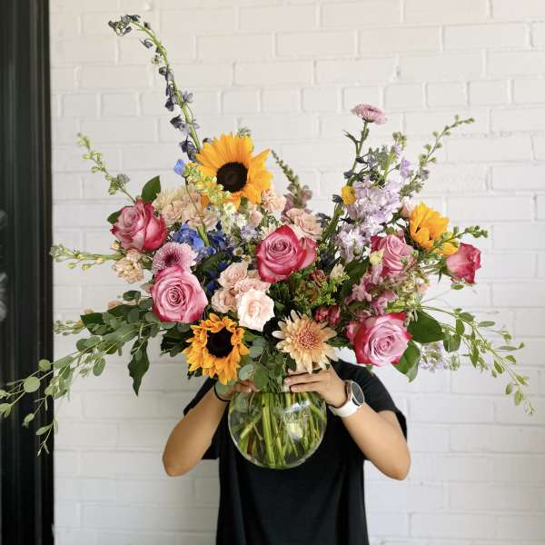 Large mixed bouquet in a glass vase with roses and sunflowers
