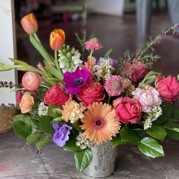 Mixed bouquet with pink roses, orange tulips, and a peach gerbera daisy in a metal vase