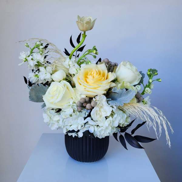 White and cream floral arrangement in a black vase