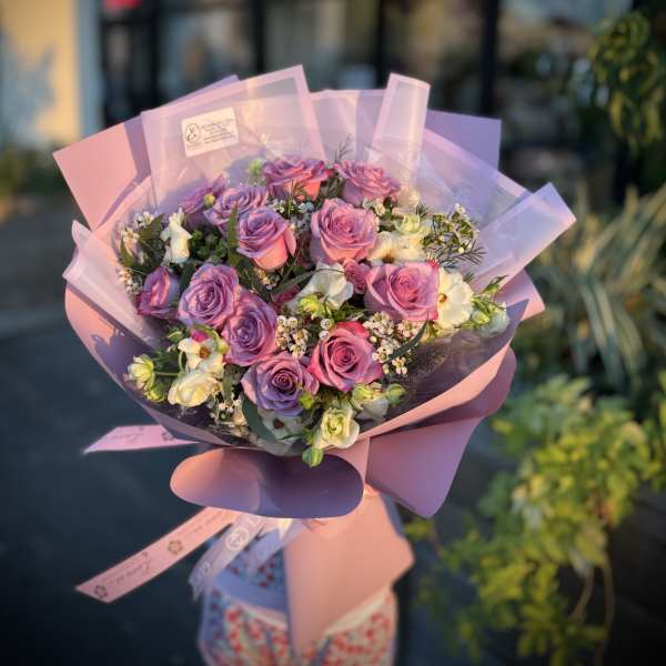Bouquet of pink and lavender roses wrapped in pastel paper