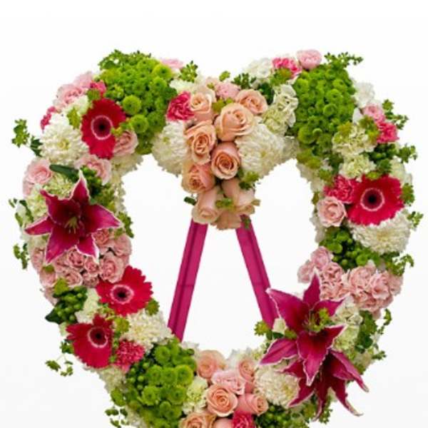 Heart-shaped floral wreath on an easel with pink and green flowers