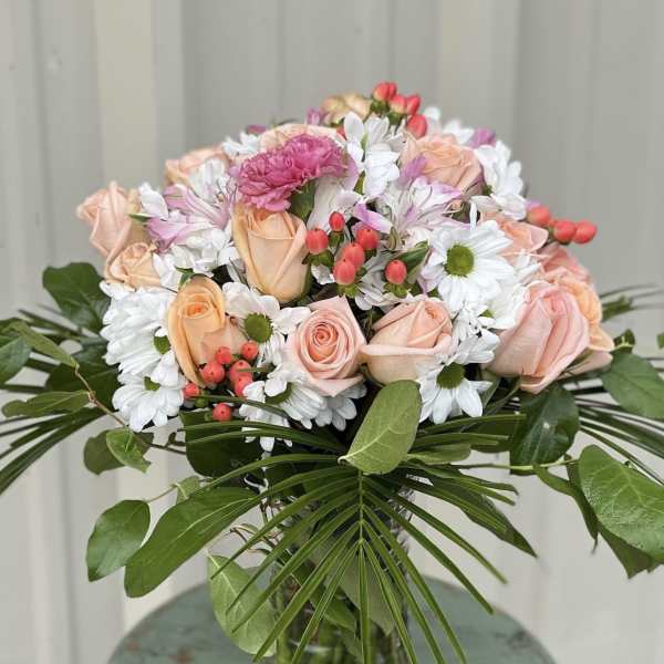 Bouquet of peach roses and white daisies in a glass vase