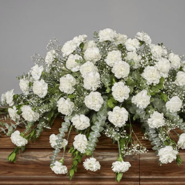 Large white carnation spray on a wooden casket