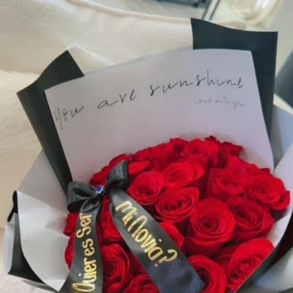 Bouquet of red roses wrapped in black and white paper with a ribbon