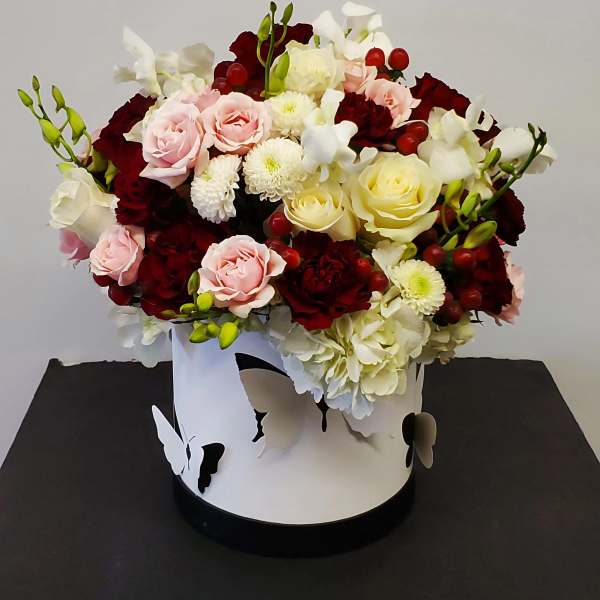 Mixed roses and white blooms in a white hatbox with butterfly cutouts