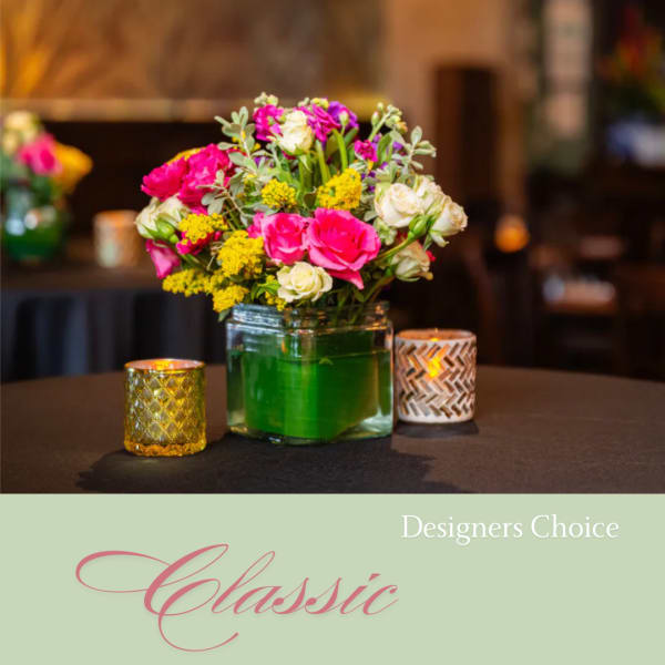 Mixed pink, white, and yellow bouquet in a glass vase with candles
