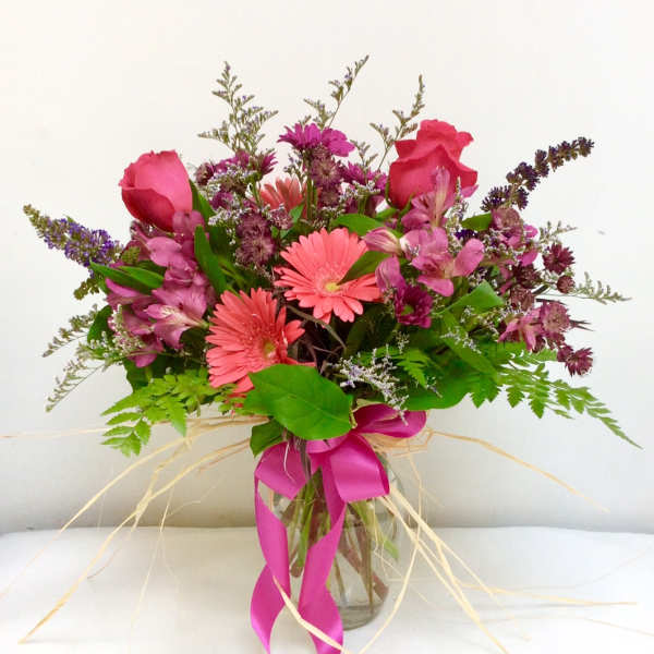 Pink and purple mixed bouquet in a glass vase with a ribbon