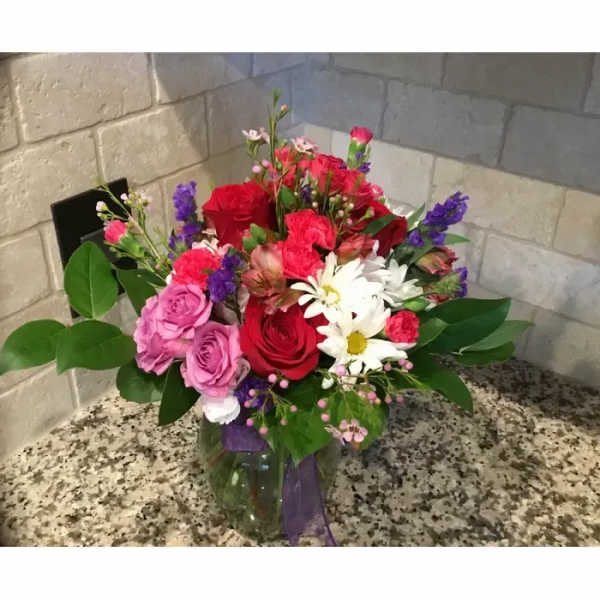 Mixed bouquet of red, pink, and white flowers in a glass vase