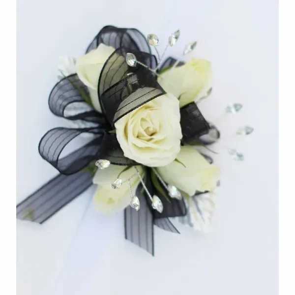White rose corsage with black ribbon and crystal accents on a white background