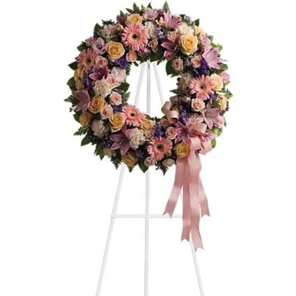 Pastel floral wreath on a white stand with pink ribbon