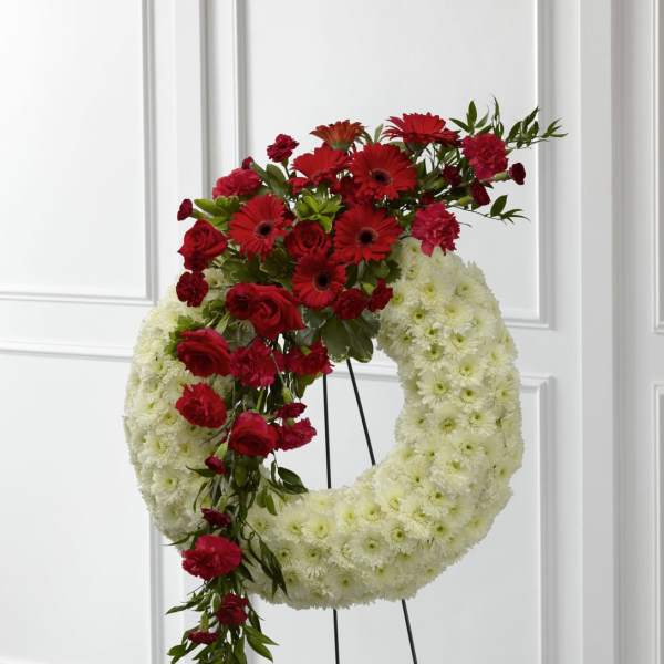 Standing white floral wreath with cascading red roses, gerberas, and carnations
