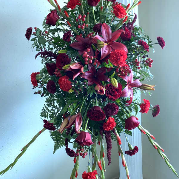 Tall burgundy floral spray with lilies, roses, and carnations