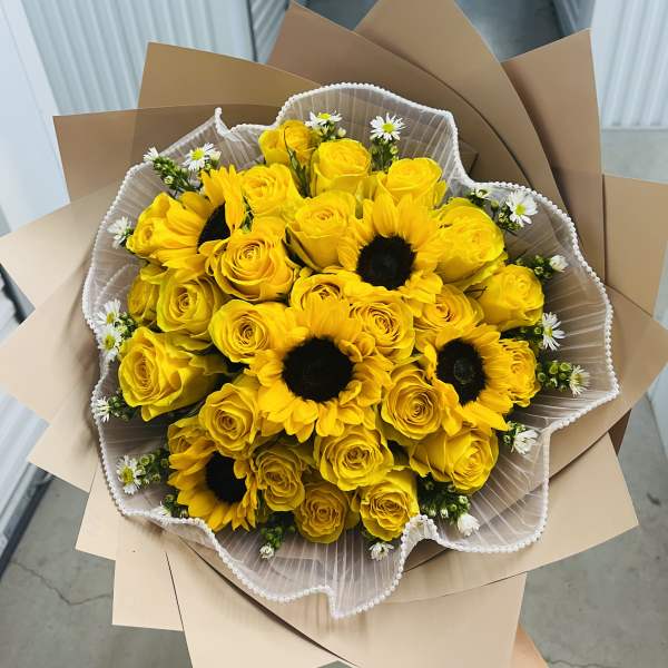 Bouquet of yellow roses and sunflowers wrapped in brown paper