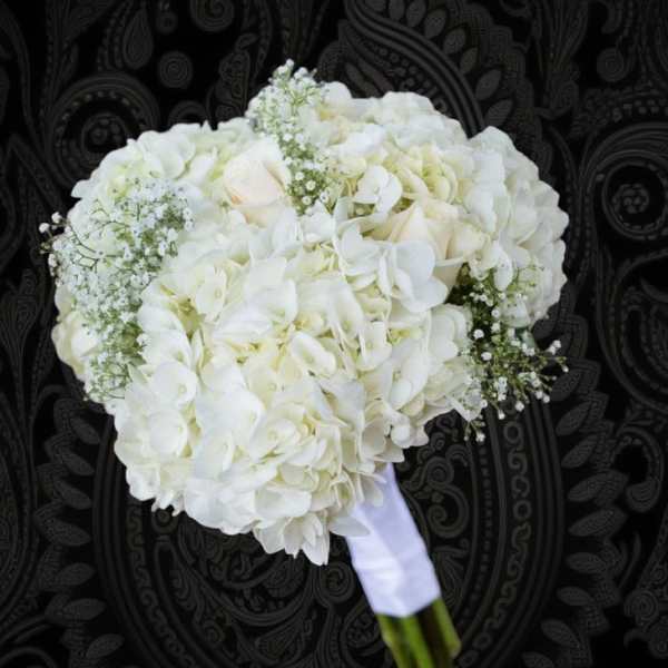 White bridal bouquet with hydrangeas and roses wrapped in white ribbon