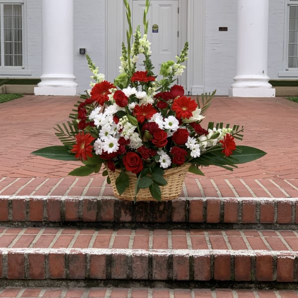 Basket arrangement of red and white flowers on brick steps