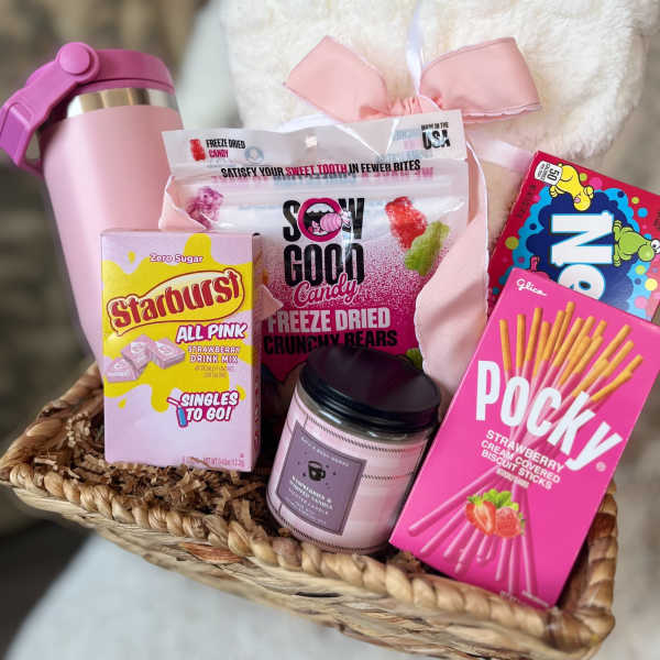 Gift basket with candy, a candle, and a pink tumbler