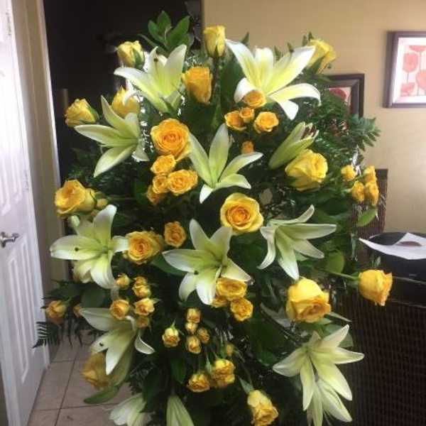 Tall standing spray of yellow roses and white lilies on an easel